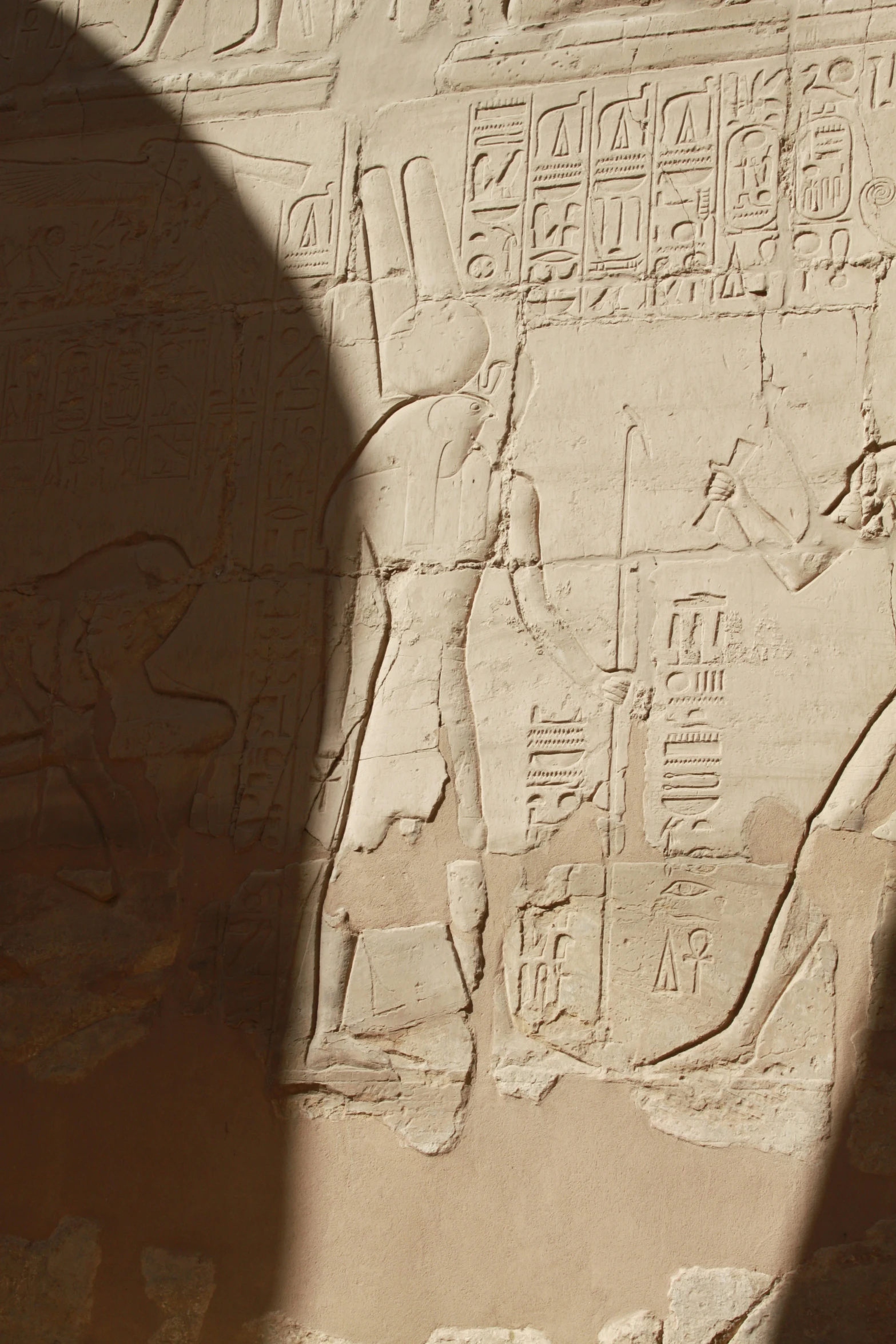 the shadow of a stone block that depicts egyptian deities