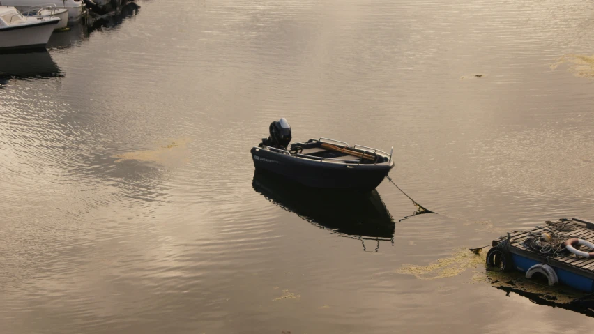 a small boat in the middle of a lake with small boats near it