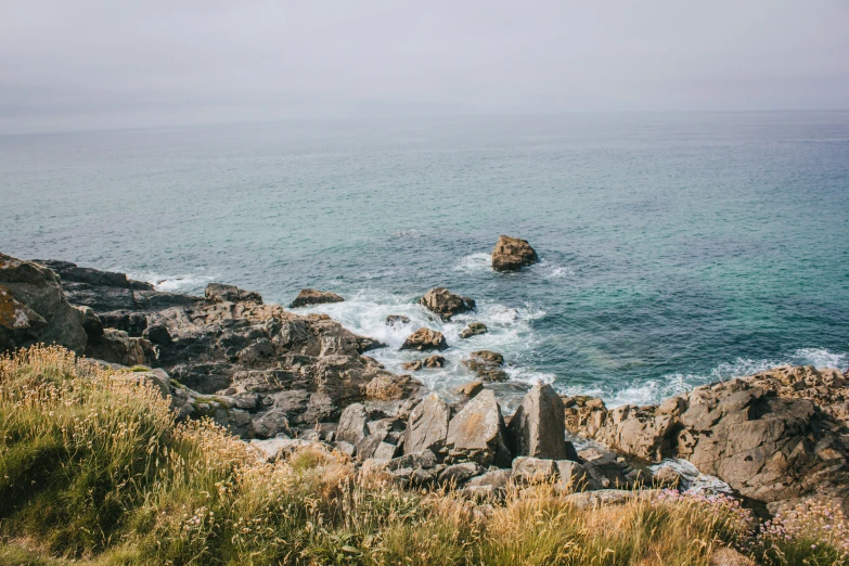 a rocky shoreline with waves crashing on the shore