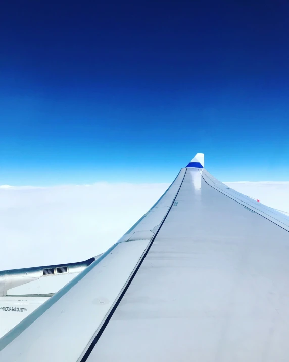 a sky view from inside an airplane with a wing