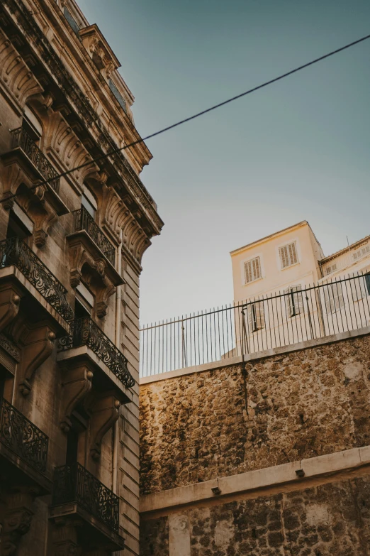 a stone building with an iron balcony next to a tall building