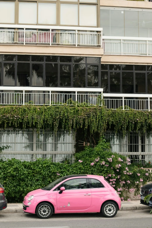 pink car parked in front of a building on a city street