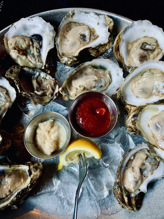 oysters on a metal platter with a little bit of er and a yellow wedge