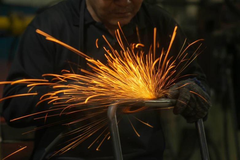 a worker using a welding tool with sparks coming from them