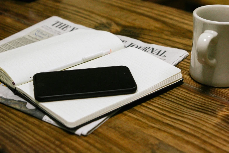 a coffee cup sits next to some paper on top of a table