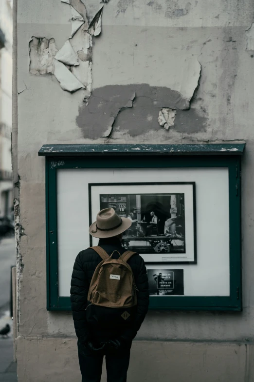 man wearing a hat staring at a destroyed framed pograph