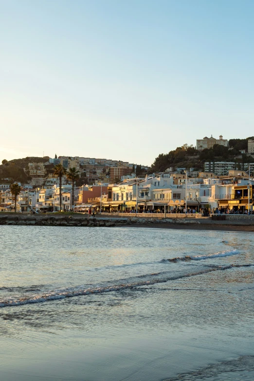 a beach next to a town on the hillside