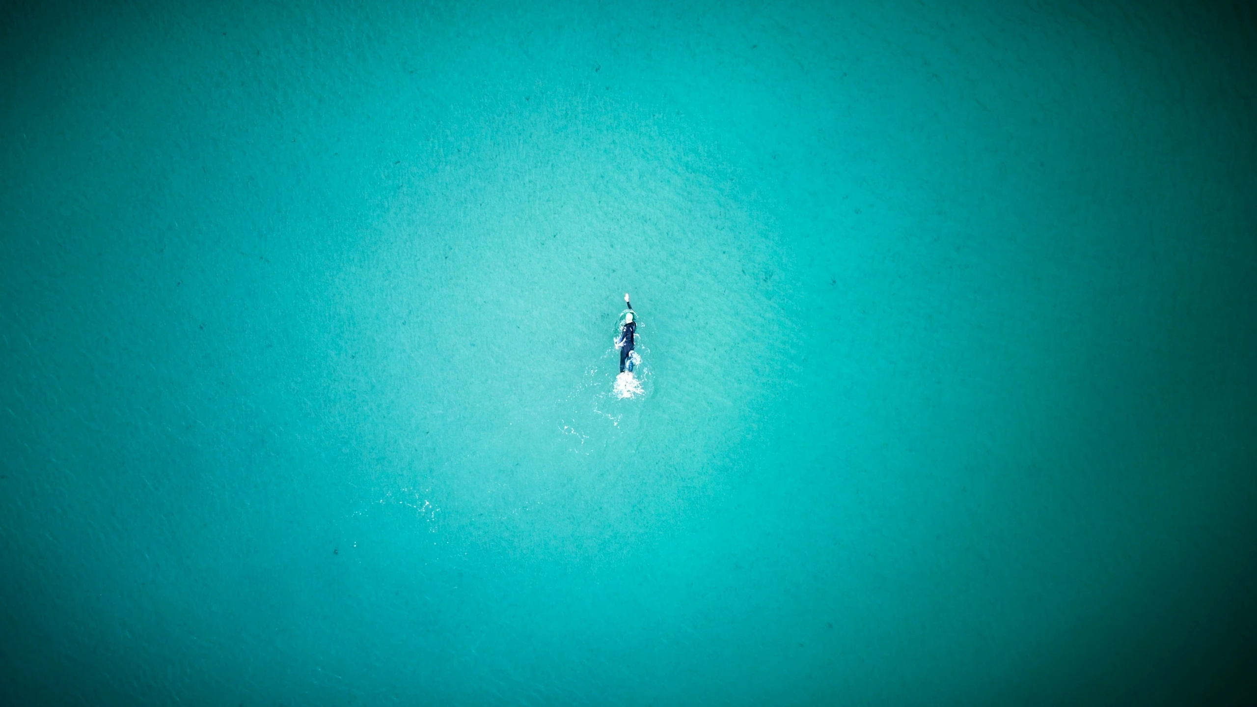 a bird's eye view of the ocean, with a single boat in the middle of the po