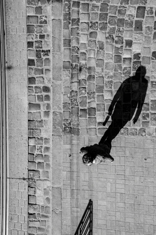 a man walks by a gate while casting a shadow on a wall