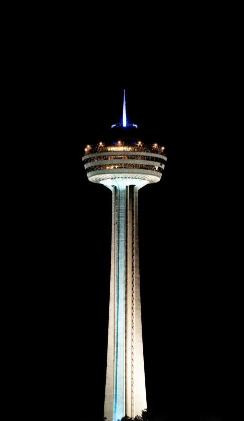 a very tall tower at night in the middle of a dark city