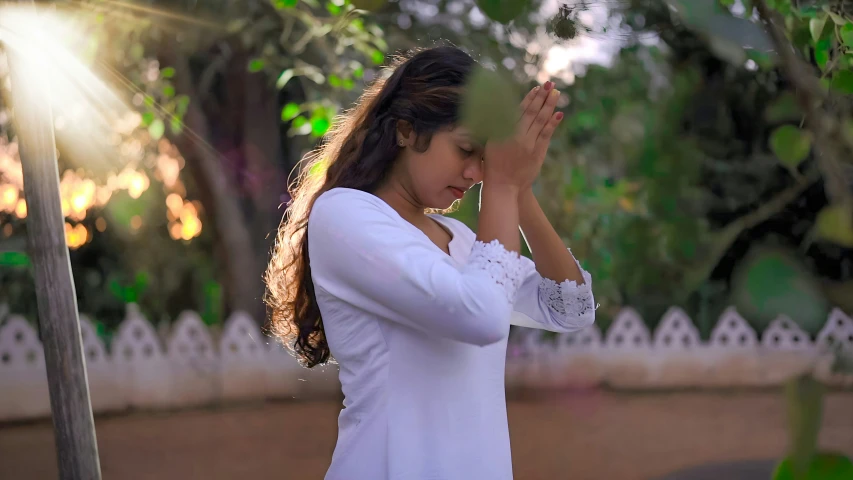 woman in white top and red shorts standing and praying