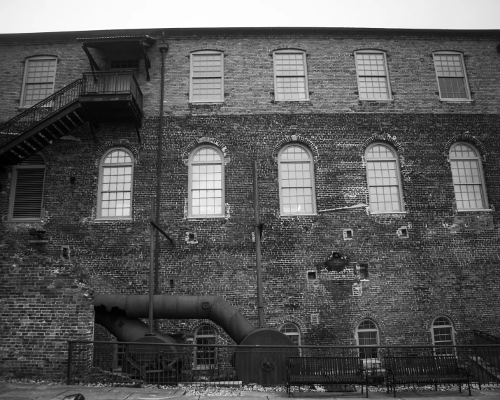 an old brick building with large window panes and wrought iron railings