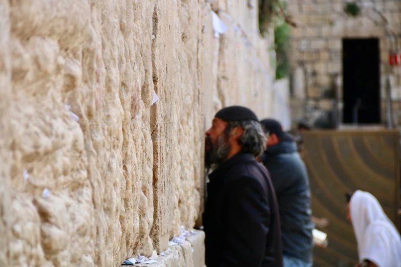 a couple of men standing in front of a tall wall