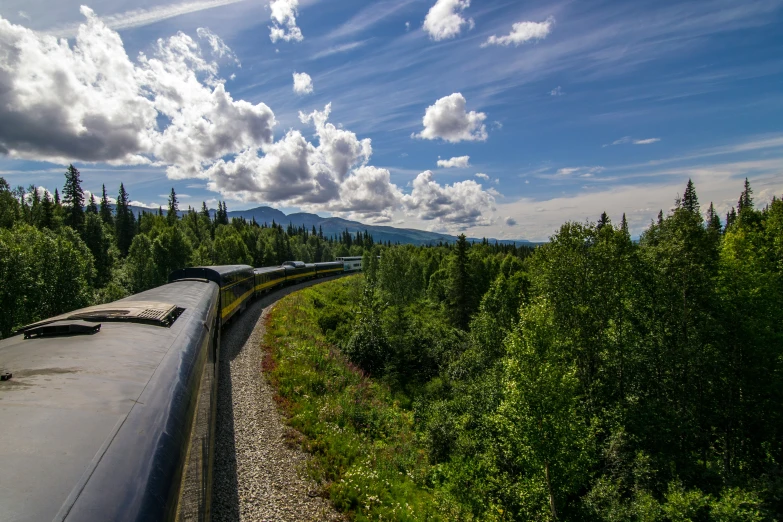 a train on tracks near trees and mountains