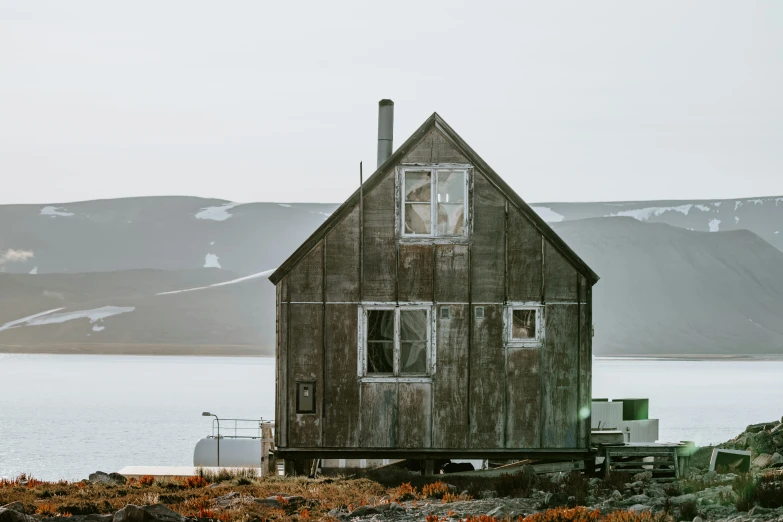 the old building is by the water with mountains in the background