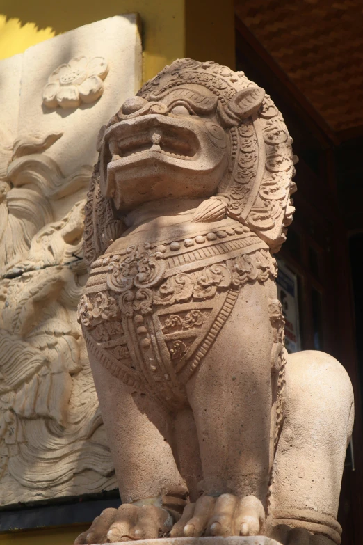 stone statue in front of ornate wall with carvings