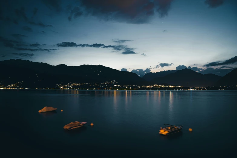 boats are floating in the lake as the night sky shines