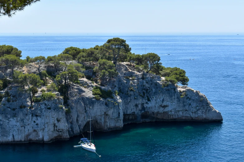 a boat floating through the blue waters next to a rocky island