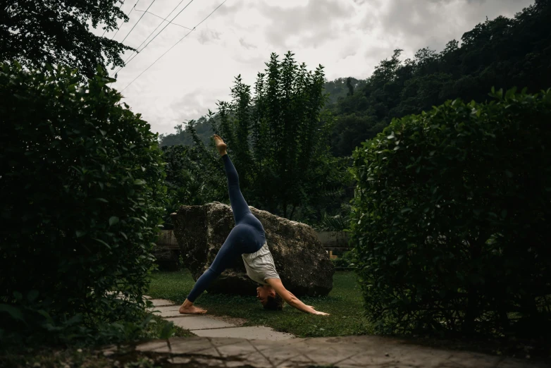 a woman doing a handstand while holding onto a rock