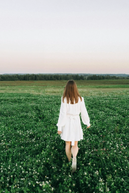 girl walking through field toward distant horizon