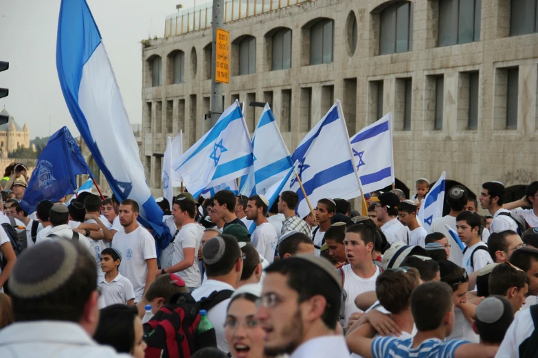 a large crowd walking down a street next to tall buildings