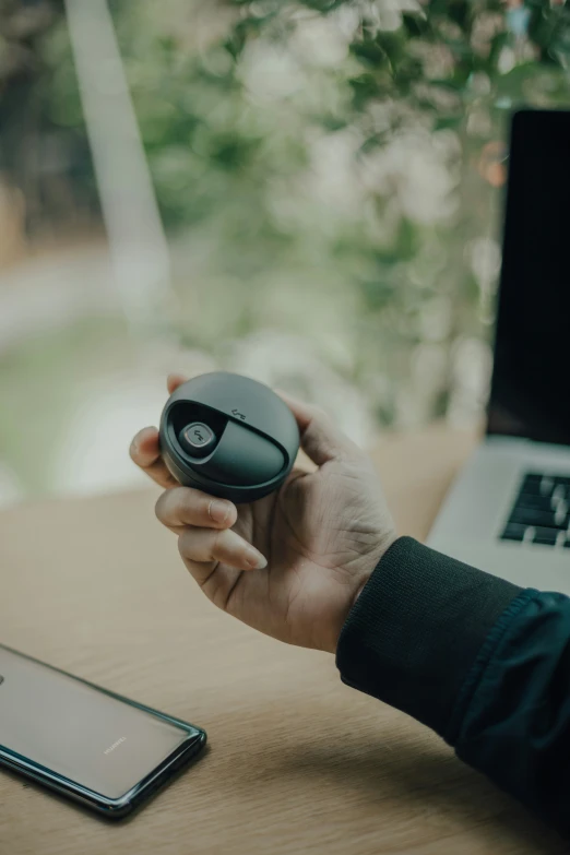 a person is holding a mouse near a laptop computer