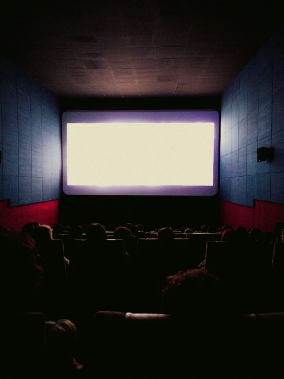 a dimly lit theater room with several people sitting in the dark