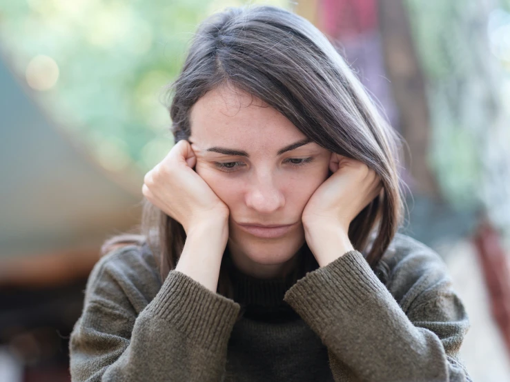 young woman with hand on her head looking sad