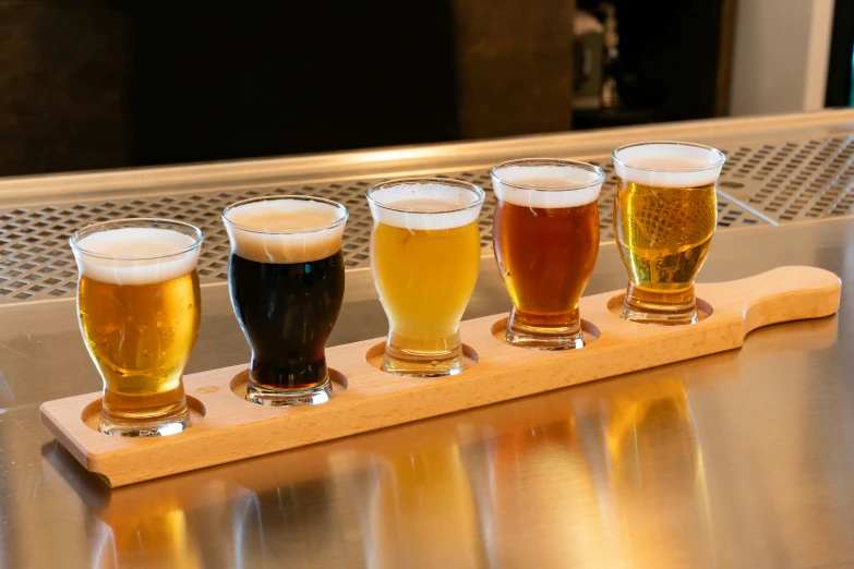 five glasses of beer are lined up in the row