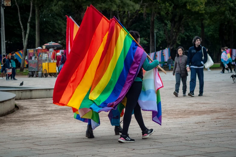 two people holding a rainbow flag on a street