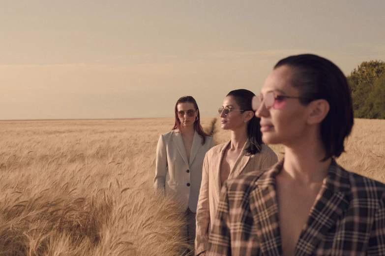 three people standing in a field with tall grass