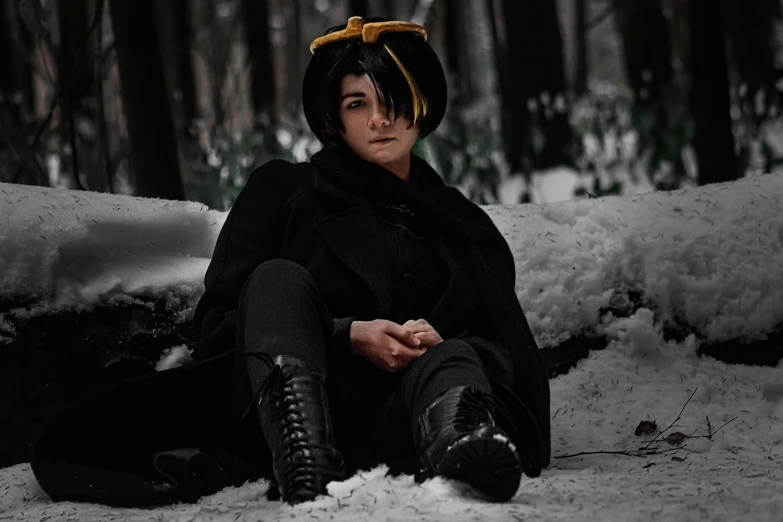 a woman sits in the snow wearing boots and a coat