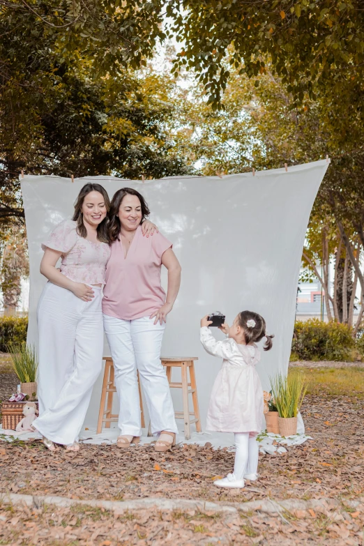 two girls and one girl taking pos in front of a white backdrop