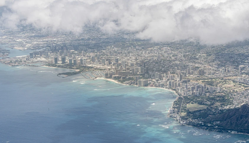 the airplane wing is flying above a city and body of water