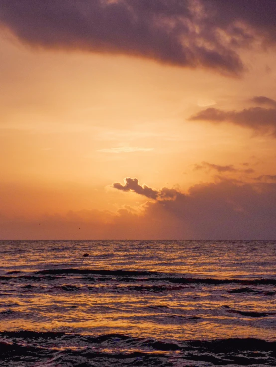 a sunset view of the ocean with a single wave