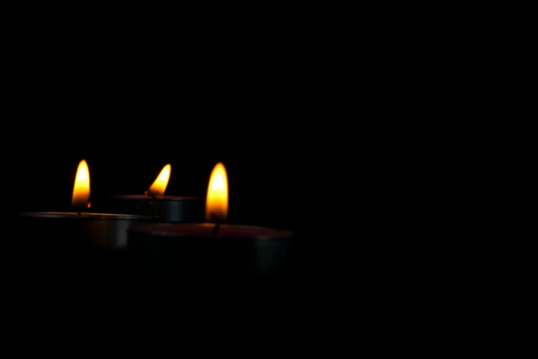 five candles glowing on black with no one around them