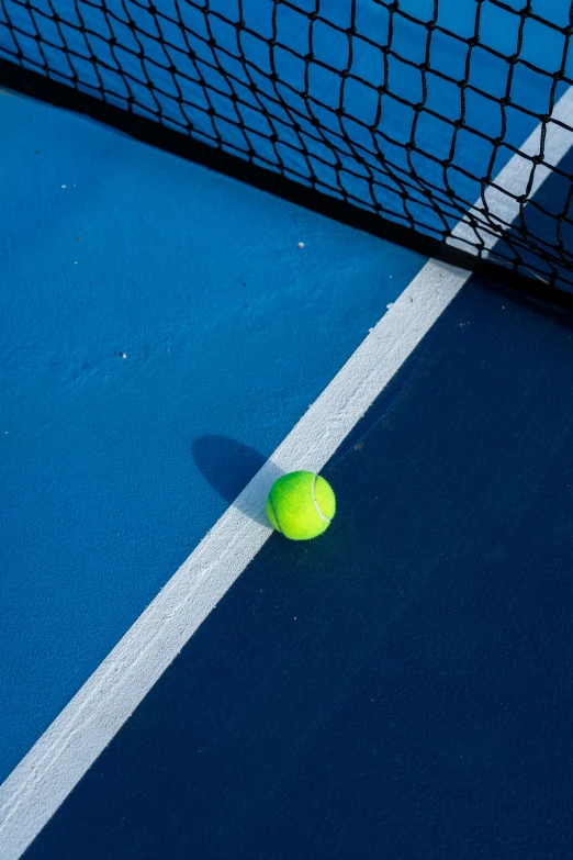 a tennis ball on the ground in front of the net