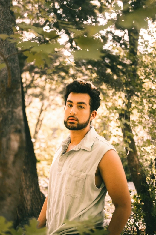 man standing in middle of forest looking away from camera