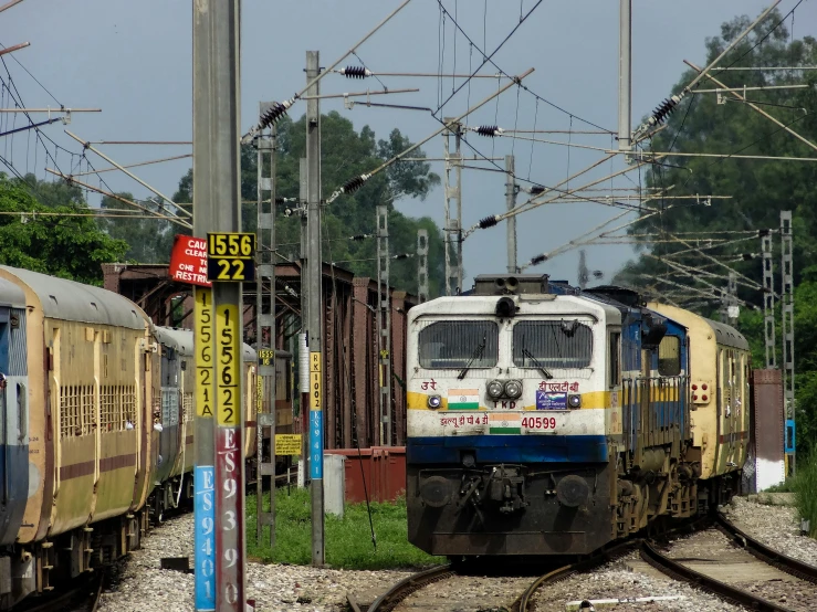 two trains parked on train tracks with wires above