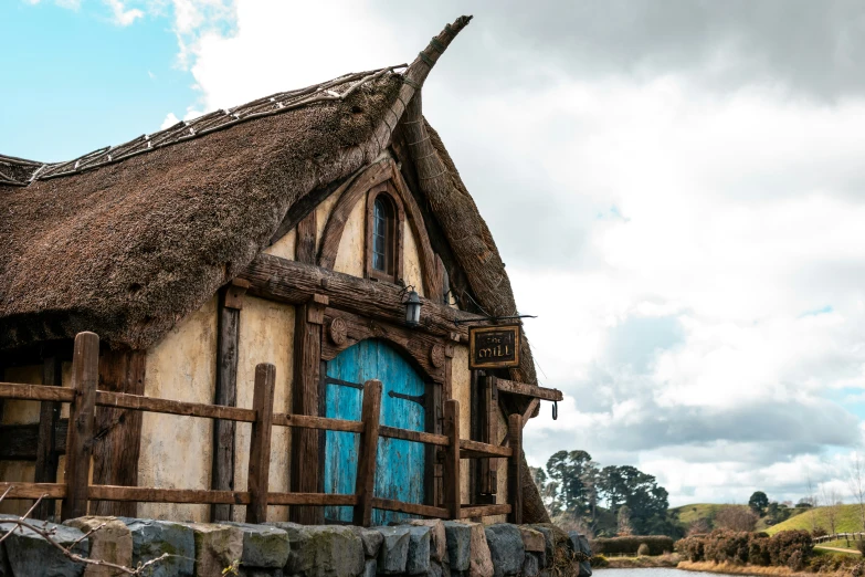 a building with a blue door and window that has a straw roof