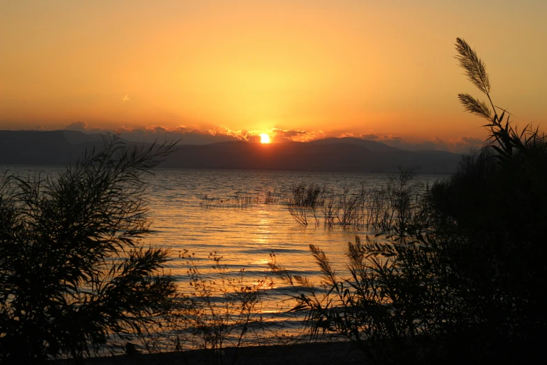 the sun is shining over the lake as it rises