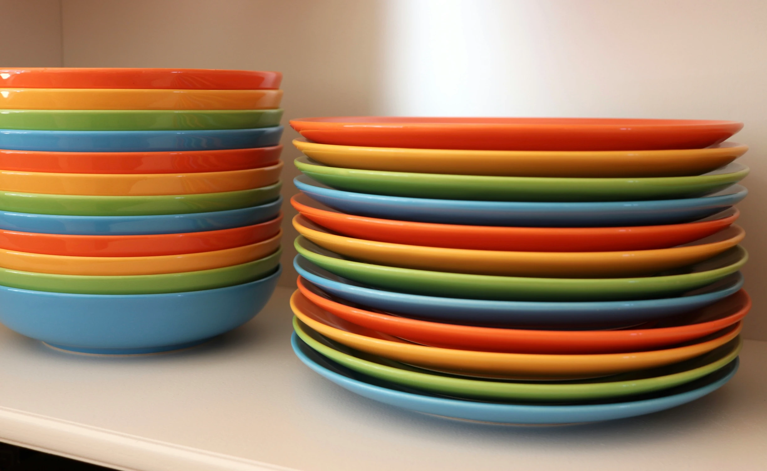 a stack of multicolored bowls on a white shelf