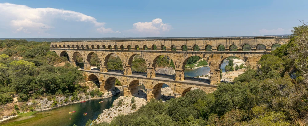 the huge bridge runs over a river in the hills