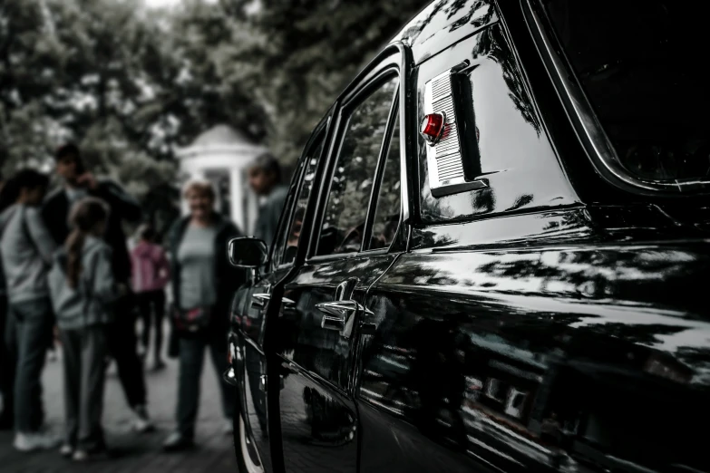 a group of people outside of a black car