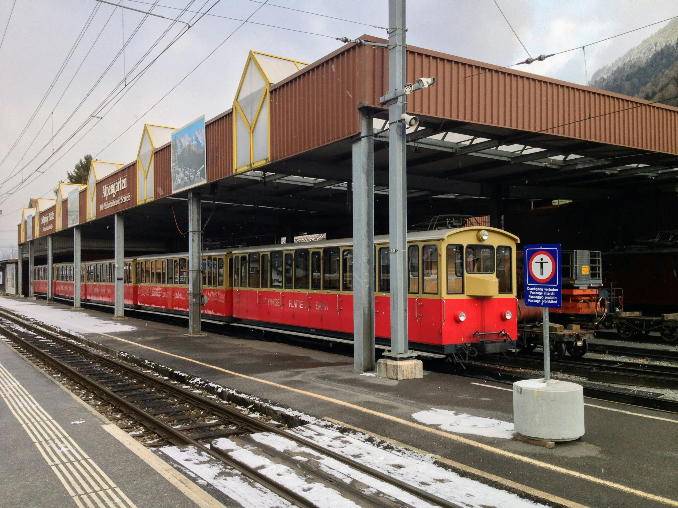 a long train on a steel track near a building