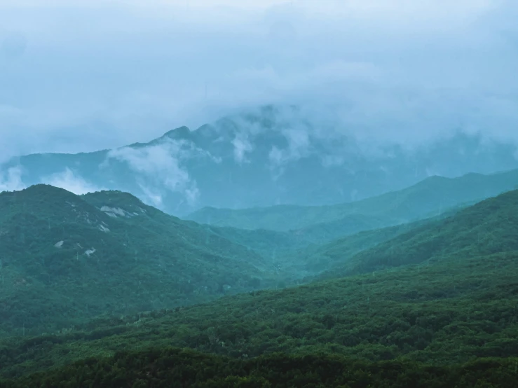 the view from the top of a mountain with a foggy mist and clouds