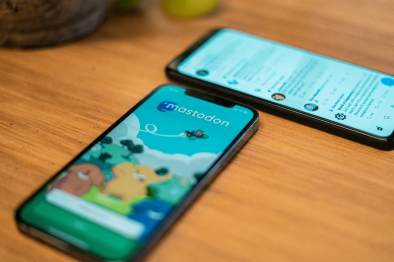 two smart phones sitting on top of a wooden table