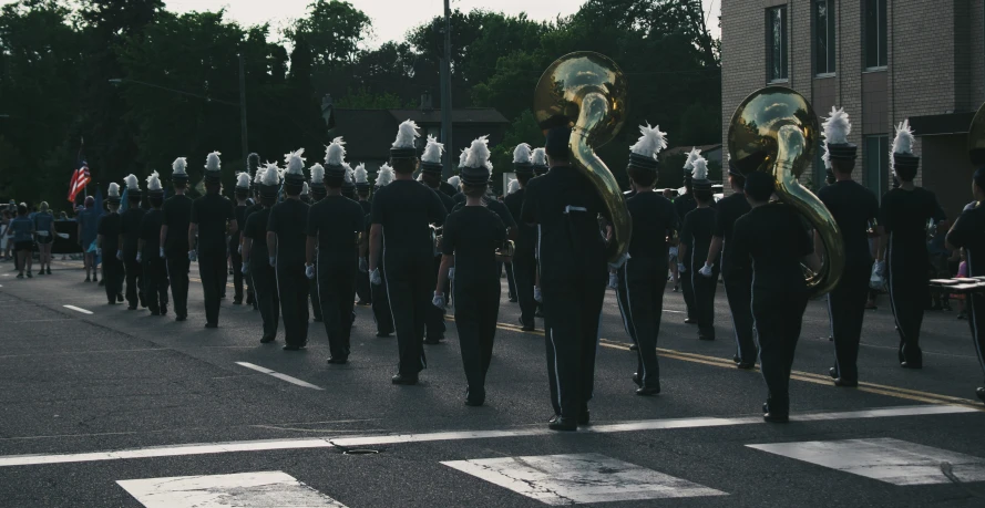 a parade being watched on the street by people in uniforms