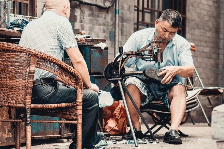 two men sit on wicker chairs, playing instruments
