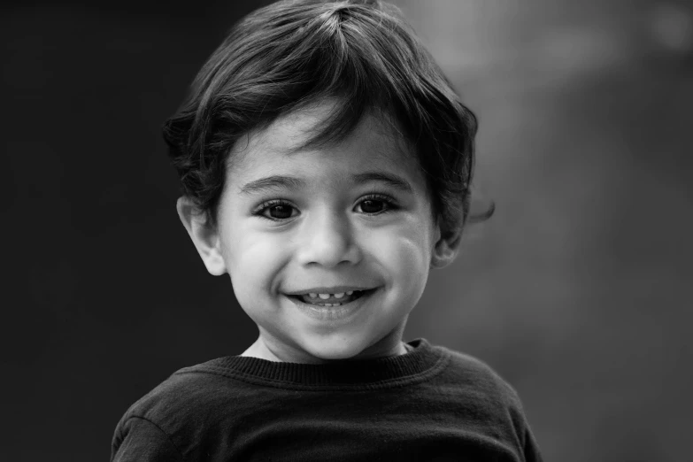 a little boy in a black shirt smiles at the camera